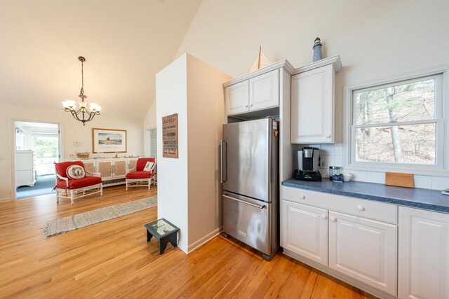 14 N Lighthouse Dr, Mears, MI 49436 - kitchen featuring decorative light fixtures, white cabinets, freestanding refrigerator, a chandelier, and light wood-style floors