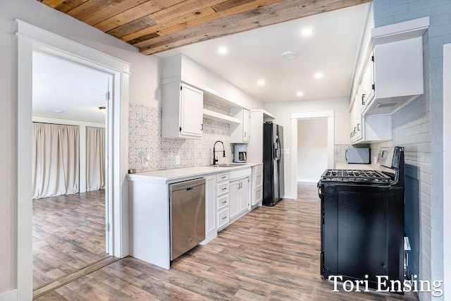 kitchen with black fridge, tasteful backsplash, stainless steel dishwasher, a sink, and range with gas stovetop