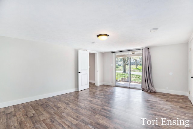 spare room with baseboards and wood finished floors