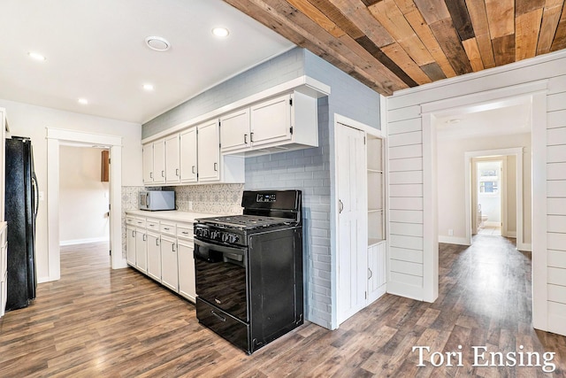 kitchen with white cabinets, light countertops, dark wood finished floors, decorative backsplash, and black appliances