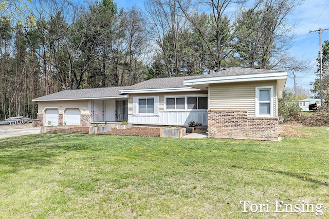 ranch-style home with a front lawn, brick siding, a shingled roof, an attached garage, and driveway