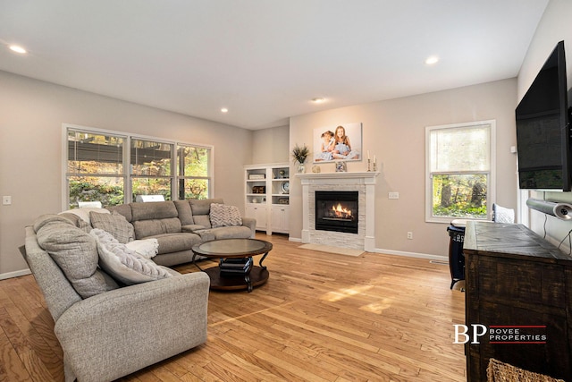 living area with a tiled fireplace, baseboards, recessed lighting, and light wood-style flooring