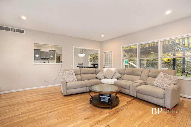 living area with baseboards, visible vents, a healthy amount of sunlight, and light wood-style flooring