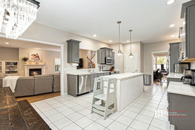 kitchen with light countertops, gray cabinets, a kitchen island, and stainless steel appliances