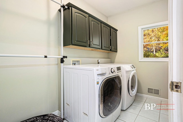 washroom featuring visible vents, washing machine and dryer, baseboards, cabinet space, and light tile patterned floors