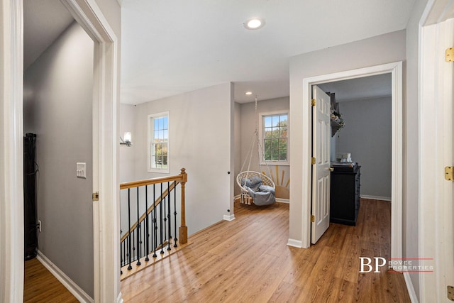 corridor with recessed lighting, baseboards, light wood-type flooring, and an upstairs landing