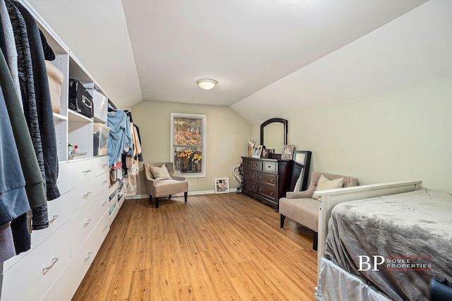 bedroom featuring baseboards, lofted ceiling, and light wood finished floors