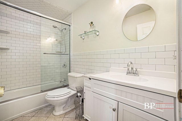 bathroom with vanity, tile patterned flooring, toilet, tile walls, and enclosed tub / shower combo