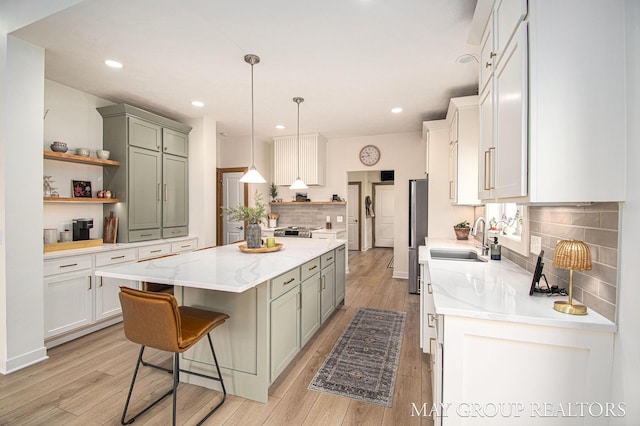 13460 Cottage View Ct, Gowen, MI 49326 - kitchen with a sink, open shelves, a center island, decorative backsplash, and light wood-style flooring