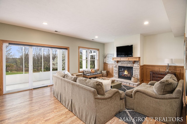13460 Cottage View Ct, Gowen, MI 49326 - living area featuring a wainscoted wall, a stone fireplace, recessed lighting, and light wood-type flooring