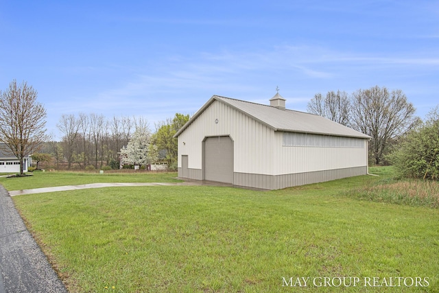 13460 Cottage View Ct, Gowen, MI 49326 - view of property exterior with an outdoor structure, a detached garage, a lawn, and metal roof
