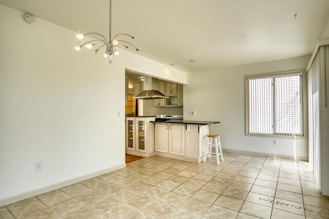 20425 Thornapple Ln, Big Rapids, MI 49307 - kitchen with dark countertops, an inviting chandelier, wall chimney exhaust hood, baseboards, and a kitchen bar