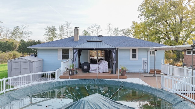 409 Louise Ave, Dowagiac, MI 49047 - rear view of property featuring an outdoor structure, a chimney, a fenced in pool, a gazebo, and a storage shed