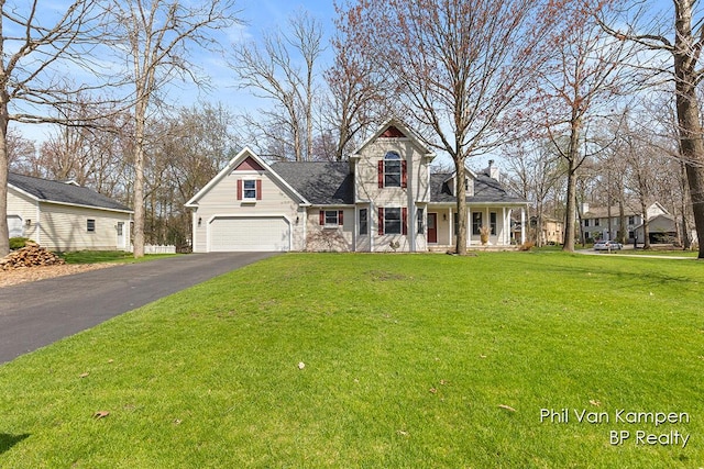 traditional-style home with covered porch, an attached garage, driveway, and a front yard