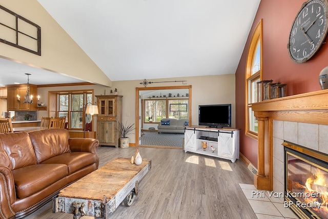 living area with a healthy amount of sunlight, baseboards, a tiled fireplace, and wood finished floors