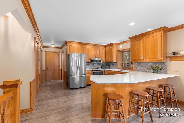 kitchen with a peninsula, light wood-style floors, light countertops, tasteful backsplash, and appliances with stainless steel finishes