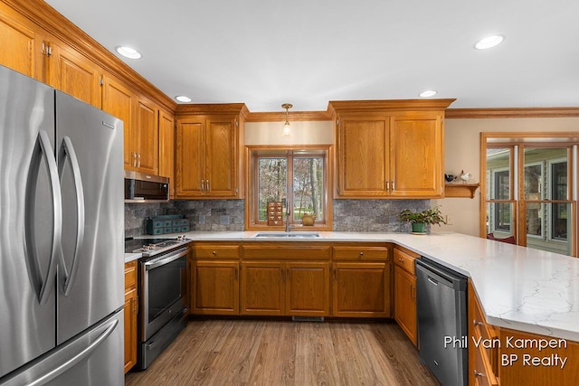 kitchen featuring brown cabinetry, decorative backsplash, a peninsula, and stainless steel appliances