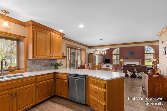 kitchen featuring ornamental molding, a peninsula, open floor plan, a chandelier, and a sink