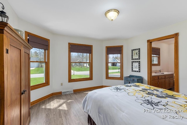 bedroom featuring a sink, baseboards, light wood finished floors, and visible vents