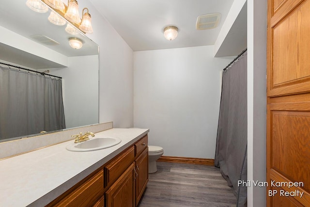 bathroom with toilet, visible vents, wood finished floors, and vanity