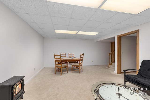 dining room with a wood stove, a drop ceiling, light carpet, and stairway