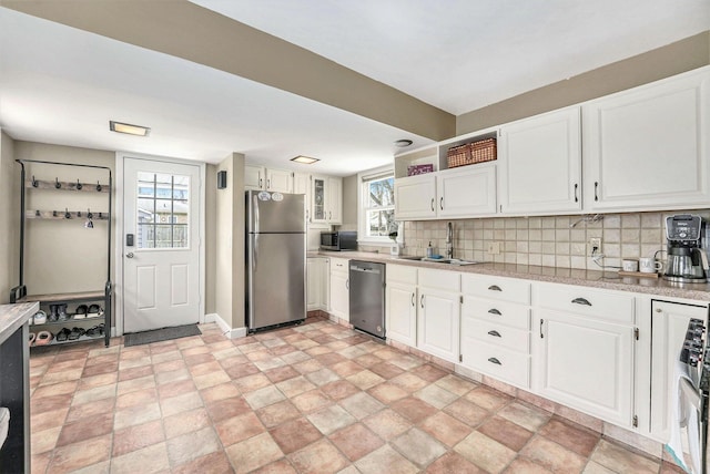 kitchen with a sink, appliances with stainless steel finishes, white cabinets, and backsplash