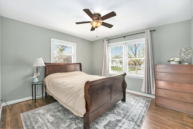 bedroom featuring baseboards, multiple windows, and wood finished floors