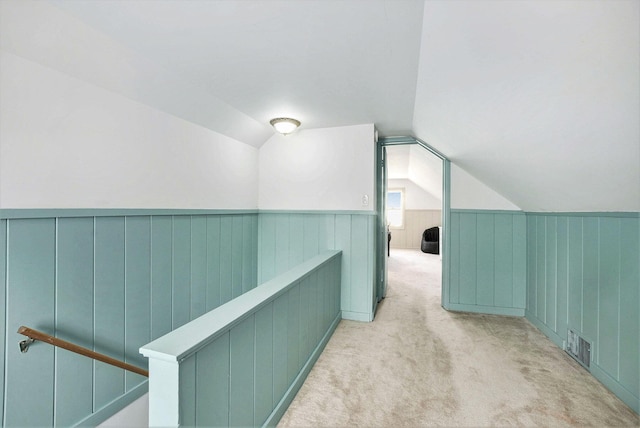 additional living space featuring a wainscoted wall, carpet, vaulted ceiling, and visible vents