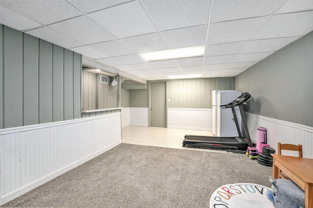 exercise room featuring a drop ceiling, visible vents, a wainscoted wall, tile patterned floors, and carpet flooring
