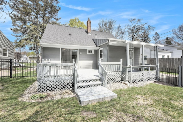 rear view of house with roof with shingles, a chimney, a yard, and fence private yard