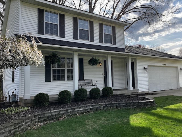 traditional-style home with a garage, covered porch, driveway, and a front yard