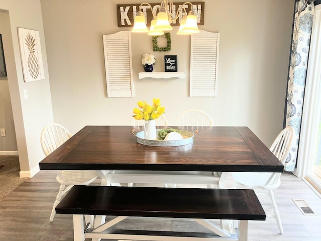 dining space featuring visible vents, baseboards, wood finished floors, and a chandelier