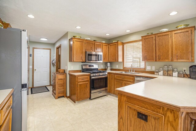 kitchen featuring brown cabinetry, light countertops, a sink, and stainless steel appliances