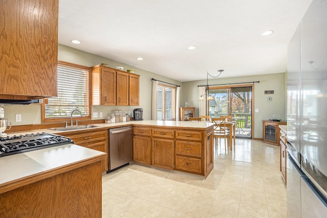 kitchen featuring brown cabinetry, dishwasher, a sink, light countertops, and a peninsula