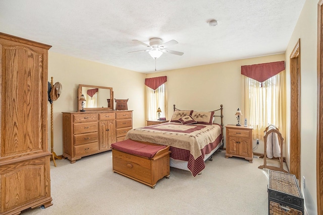 bedroom featuring a textured ceiling, ceiling fan, and light carpet