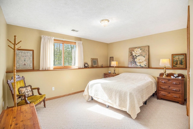 bedroom featuring a textured ceiling, baseboards, visible vents, and carpet