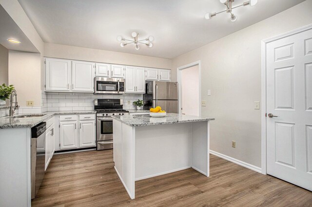 kitchen featuring a sink, appliances with stainless steel finishes, wood finished floors, and white cabinets