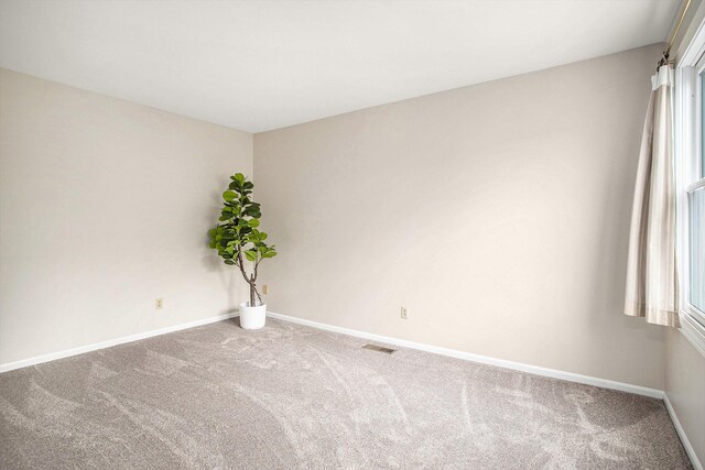 unfurnished room featuring baseboards, carpet, visible vents, and a healthy amount of sunlight