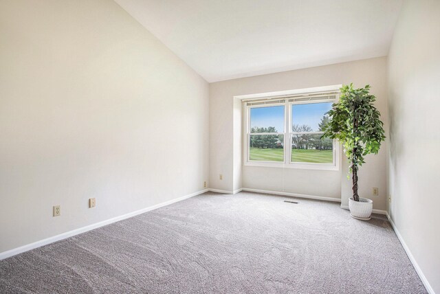 spare room featuring baseboards, lofted ceiling, and carpet