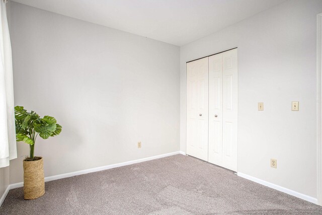 unfurnished bedroom featuring baseboards, carpet, and a closet