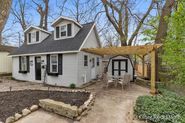 view of front of house featuring roof with shingles, a storage unit, fence, an outbuilding, and a patio