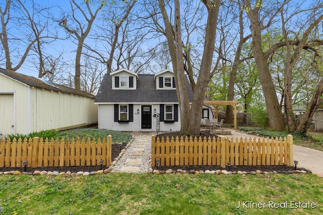 cape cod-style house with an outbuilding, a shingled roof, and fence private yard