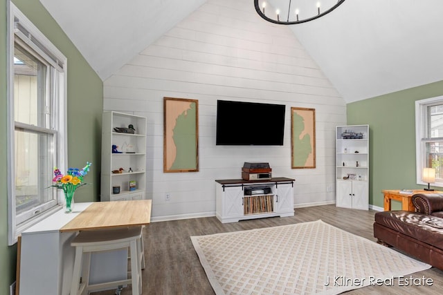living area with baseboards, wood finished floors, and lofted ceiling