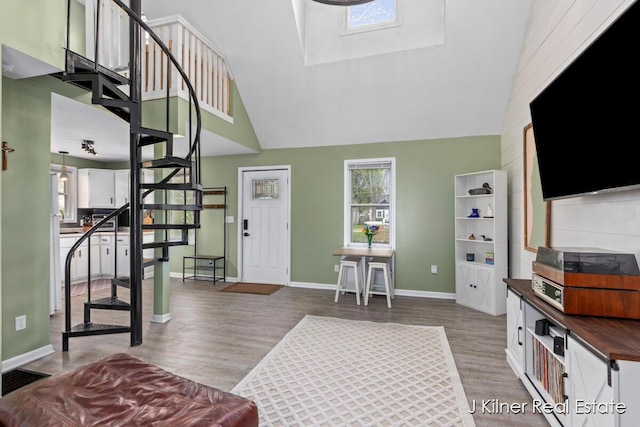 living room featuring baseboards, stairs, wood finished floors, and a towering ceiling