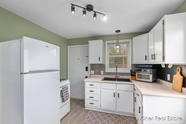 kitchen with a sink, tasteful backsplash, white appliances, and white cabinets
