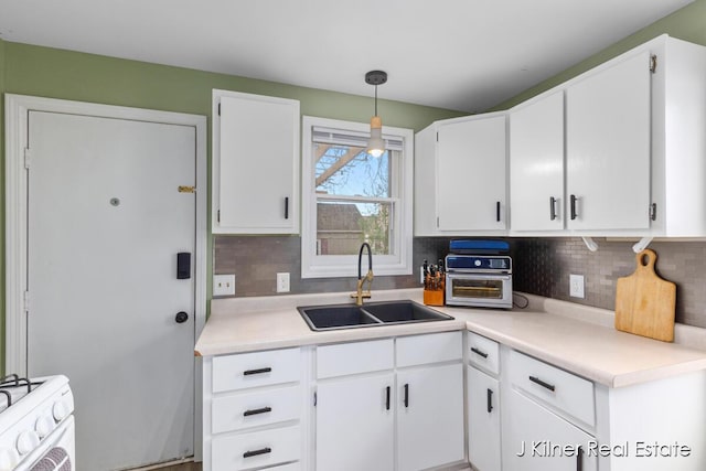 kitchen with a sink, backsplash, white range with gas stovetop, and white cabinetry