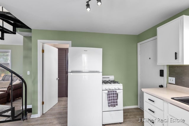 kitchen featuring light countertops, light wood finished floors, white appliances, and white cabinetry