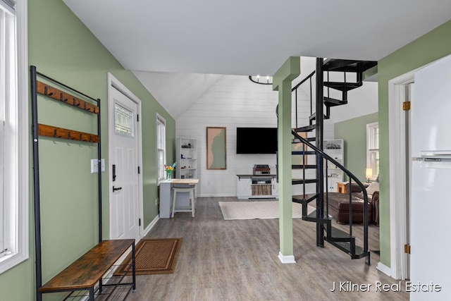 entryway featuring lofted ceiling, wood finished floors, baseboards, stairway, and plenty of natural light