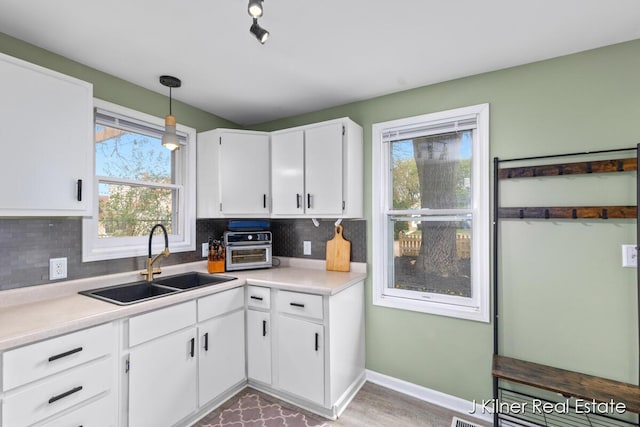 kitchen with light countertops, white cabinetry, decorative backsplash, and a sink
