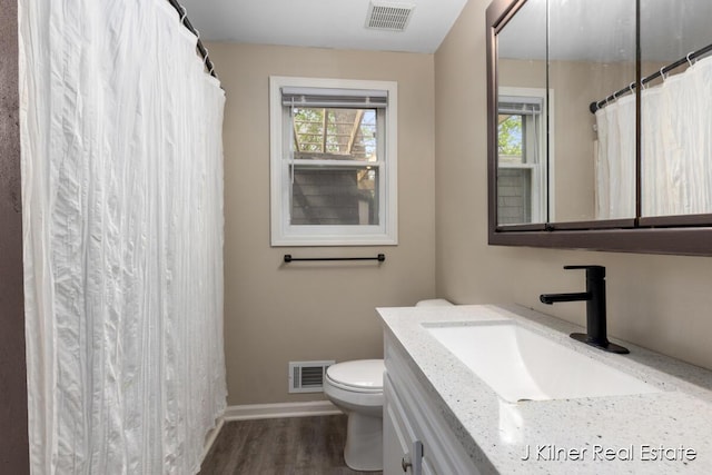 bathroom featuring visible vents, baseboards, wood finished floors, and toilet